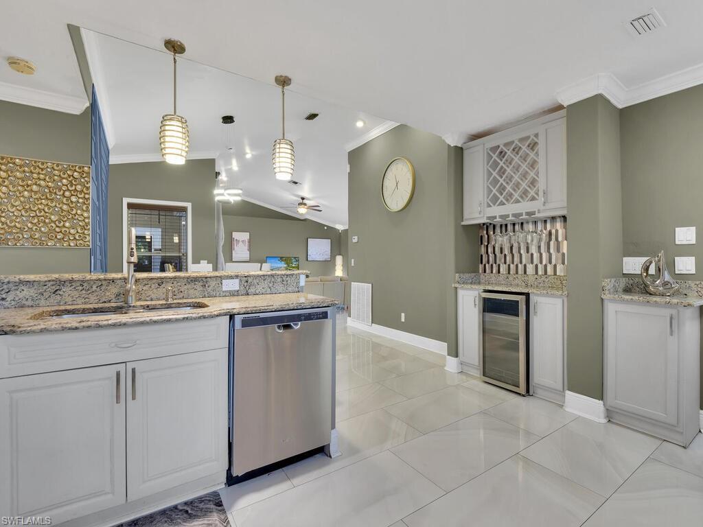 Kitchen with dishwasher, sink, wine cooler, vaulted ceiling, and white cabinetry