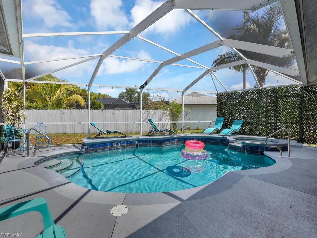 View of swimming pool with an in ground hot tub, a patio, and glass enclosure
