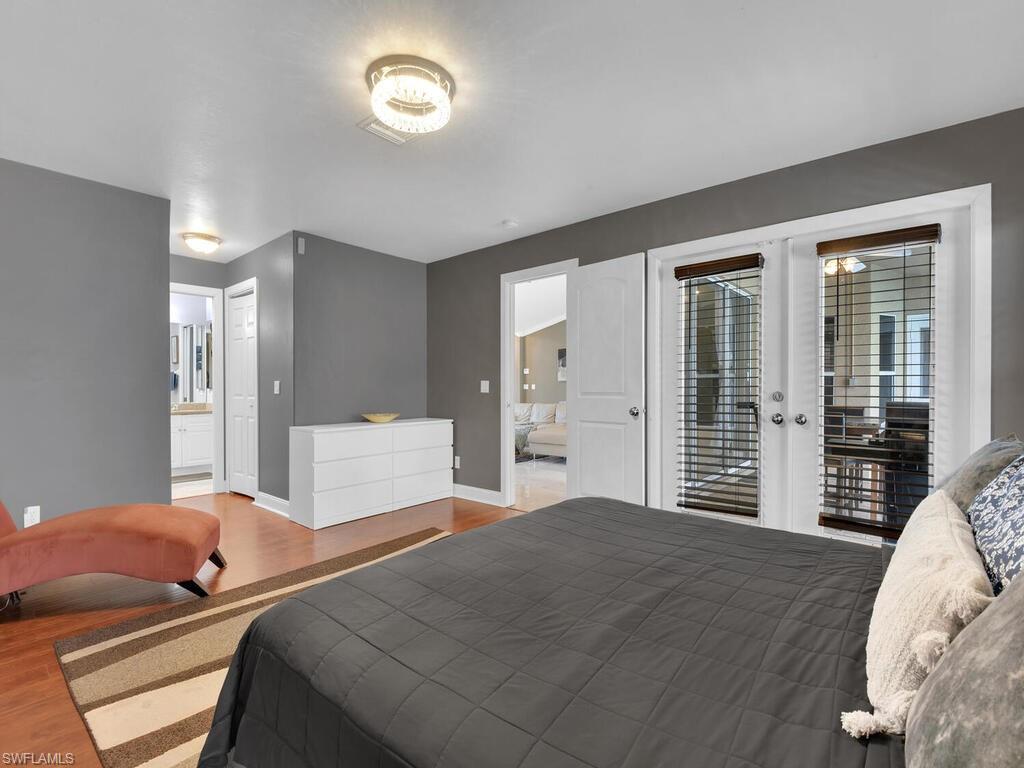 Bedroom with french doors, connected bathroom, hardwood / wood-style flooring, and access to outside