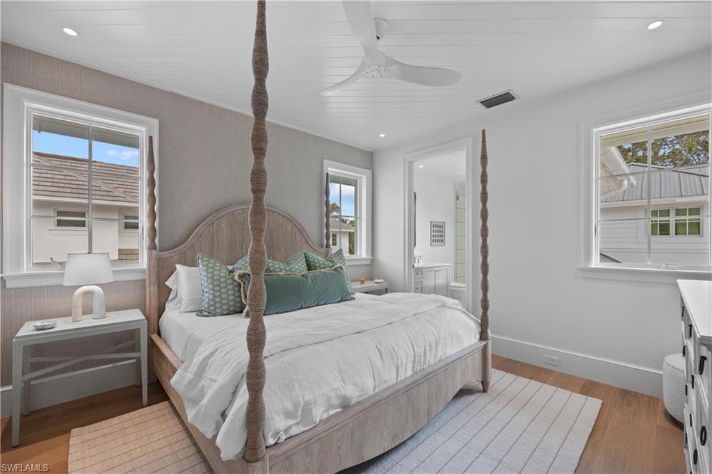 Bedroom featuring ensuite bathroom, wooden ceiling, multiple windows, and light hardwood / wood-style flooring