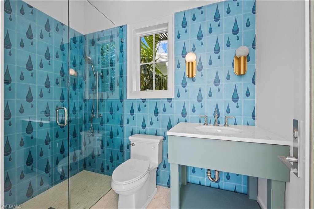 Bathroom featuring tile walls, toilet, vanity, and an enclosed shower