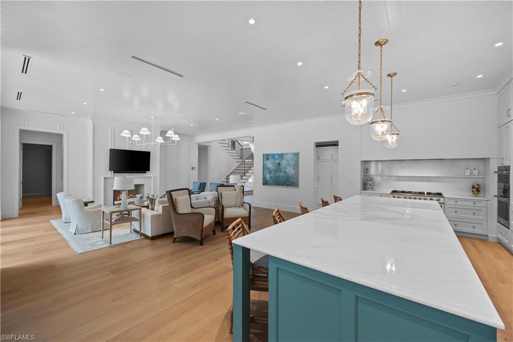 Kitchen with light hardwood / wood-style floors, crown molding, white cabinetry, and pendant lighting