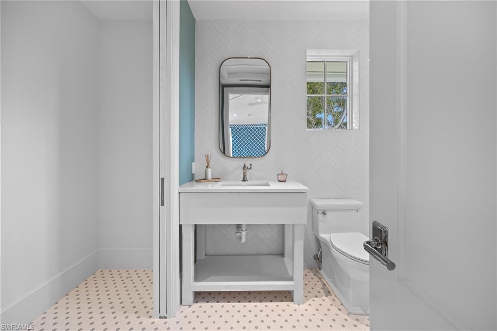 Bathroom with toilet, tile patterned floors, and sink