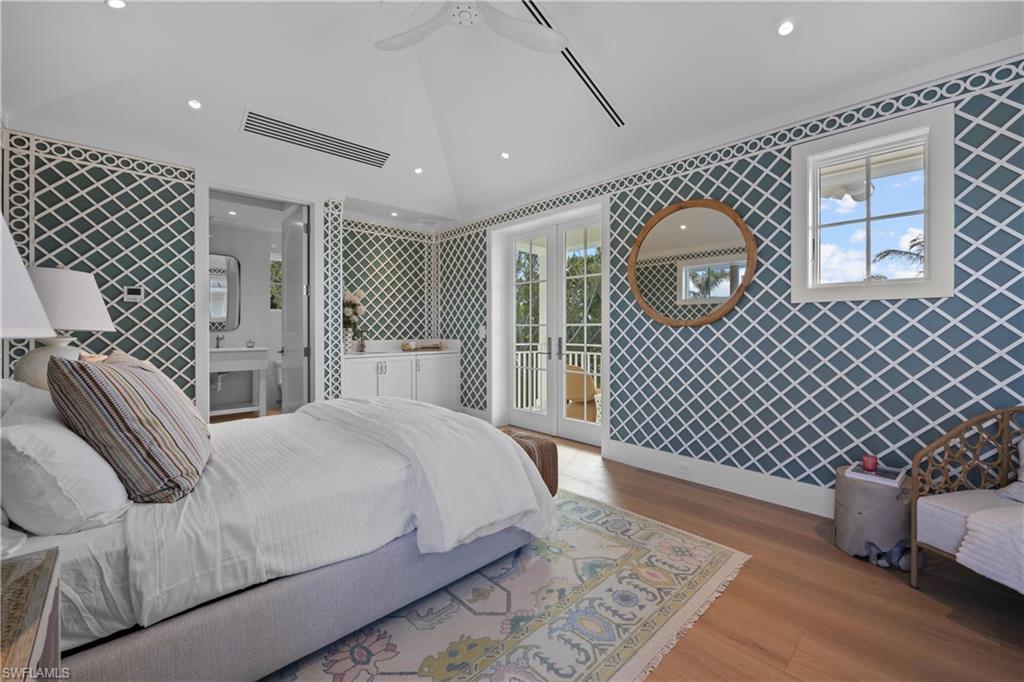 Bedroom with lofted ceiling, access to outside, light wood-type flooring, ceiling fan, and ensuite bathroom