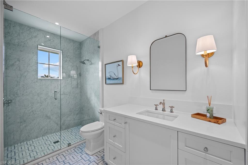 Bathroom featuring toilet, vanity, tile patterned floors, and a shower with door