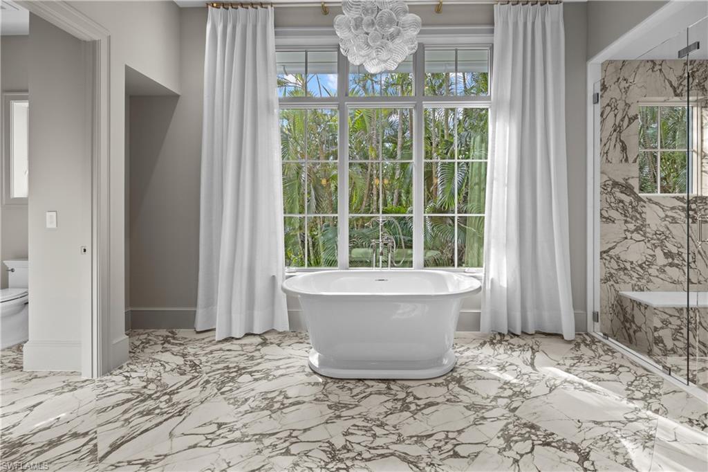 Bathroom with toilet, a washtub, and a notable chandelier