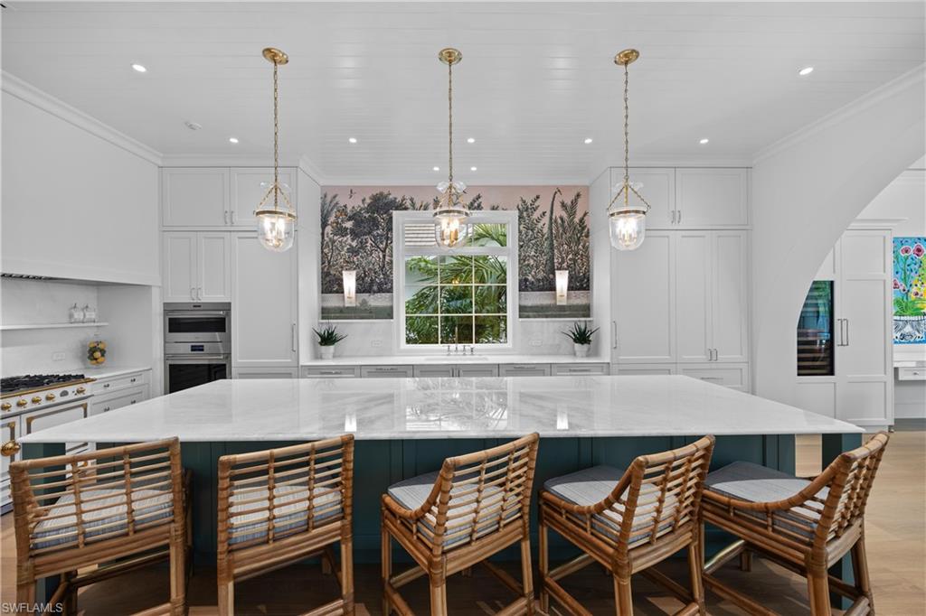 Kitchen with a breakfast bar, white cabinets, a spacious island, and decorative light fixtures
