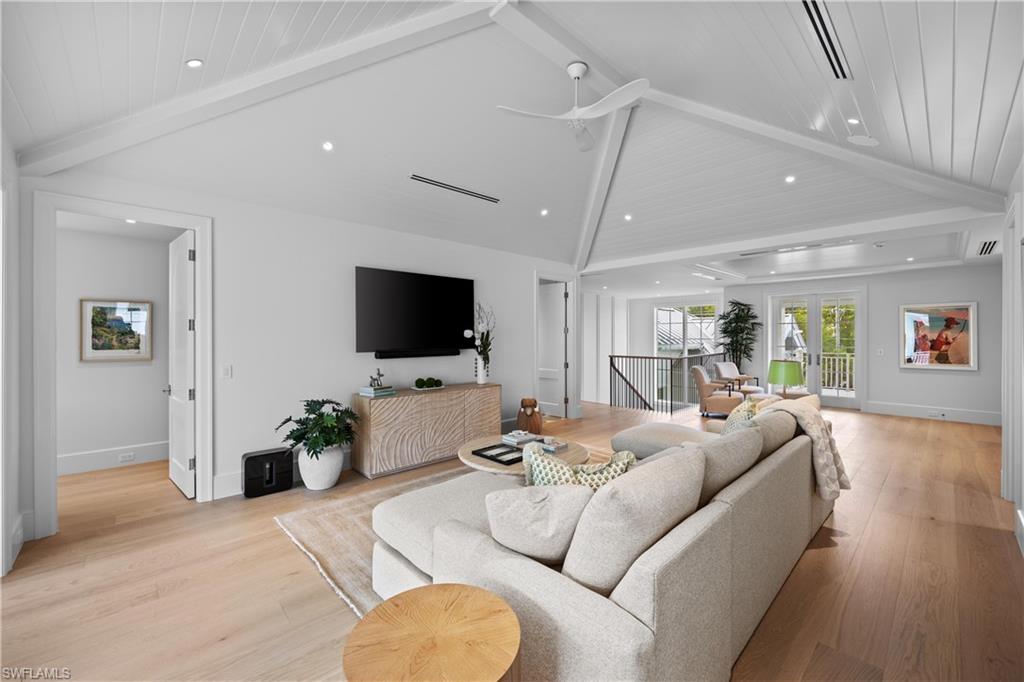 Living room featuring ceiling fan, vaulted ceiling with beams, french doors, and light wood-type flooring