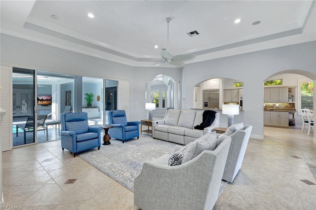 Living room with a tray ceiling, ceiling fan, and crown molding