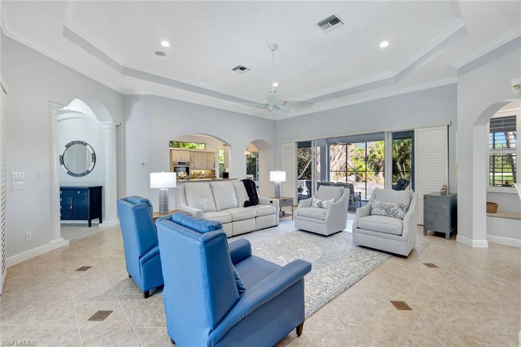 Living room with ceiling fan, a healthy amount of sunlight, ornamental molding, and a tray ceiling