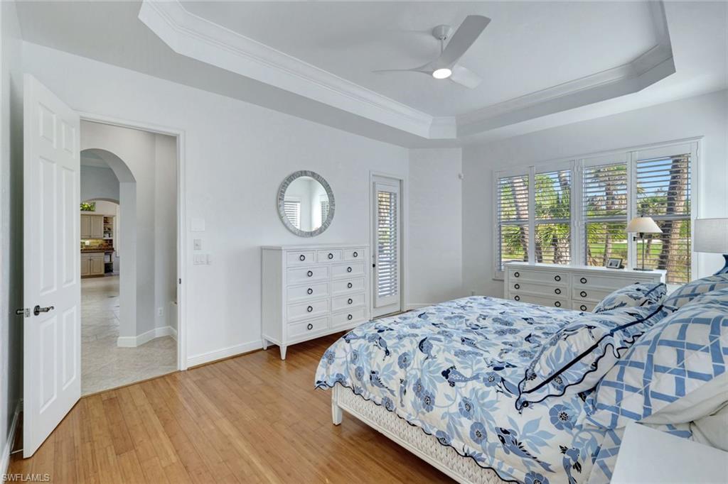 Bedroom with hardwood / wood-style flooring, a raised ceiling, ceiling fan, tray ceiling and ornamental molding