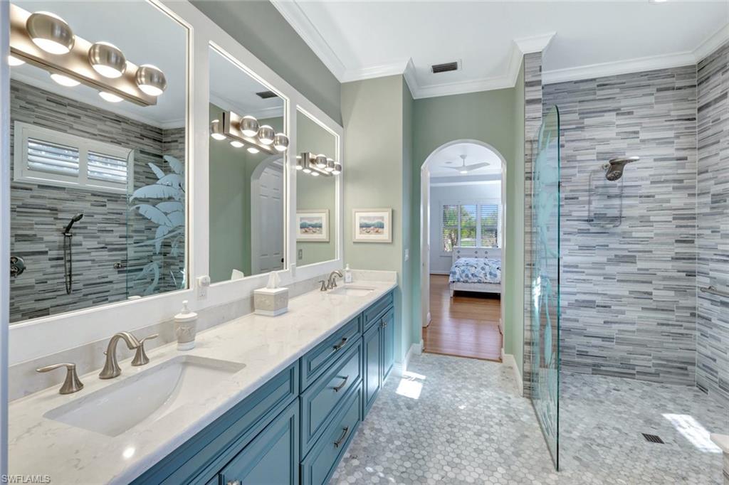 Bathroom featuring vanity, crown molding, ceiling fan, tiled walk-in shower, and tile floor