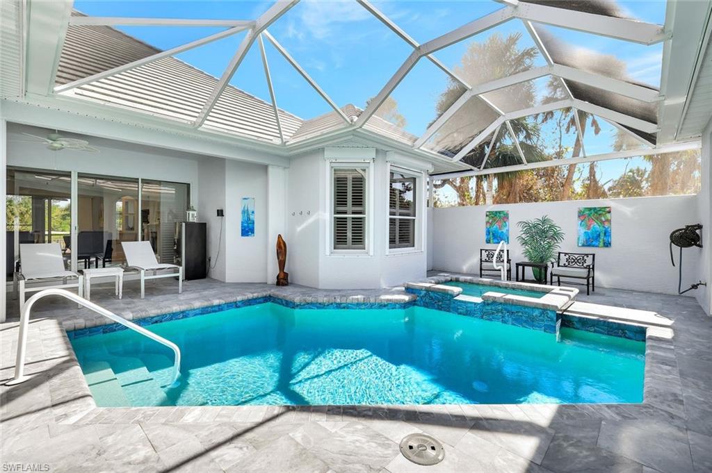 View of screened-in pool + spa with a lanai, a patio area