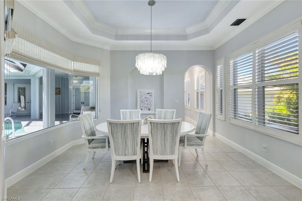 Dining room with a notable chandelier, plenty of natural light, ornamental molding, and light tile patterned floors