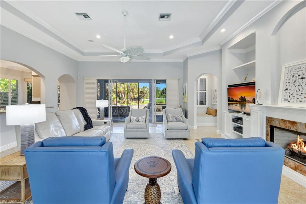 Living room featuring a fireplace, a wealth of natural light, ornamental molding, and ceiling fan