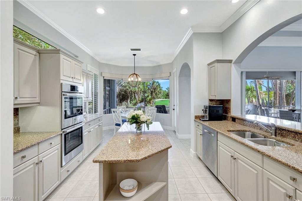 Kitchen with light stone countertops, sink, stainless steel appliances, and ornamental molding