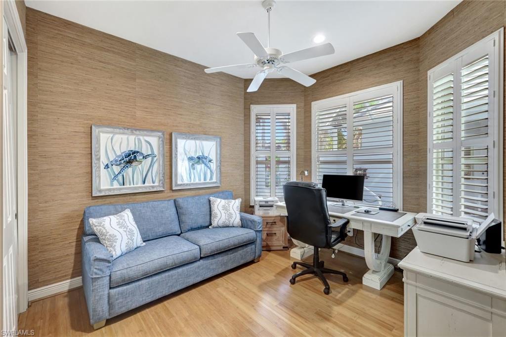 Office space featuring light hardwood / wood-style floors and ceiling fan overlooking pool + spa