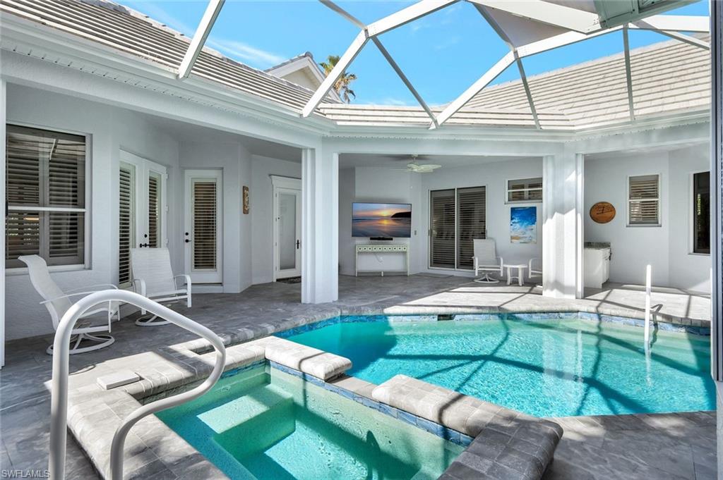 View of pool with an in ground hot tub, a patio, glass enclosure, and ceiling fan