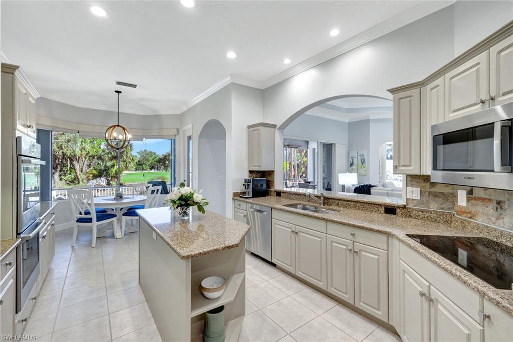 Kitchen with plenty of natural light, light stone counters, decorative backsplash, and appliances with stainless steel finishes