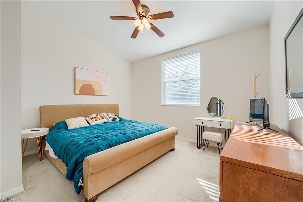 Bedroom with ceiling fan, light colored carpet, and vaulted ceiling