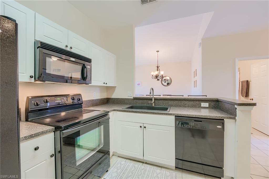 Kitchen featuring sink, kitchen peninsula, a chandelier, white cabinets, and black appliances