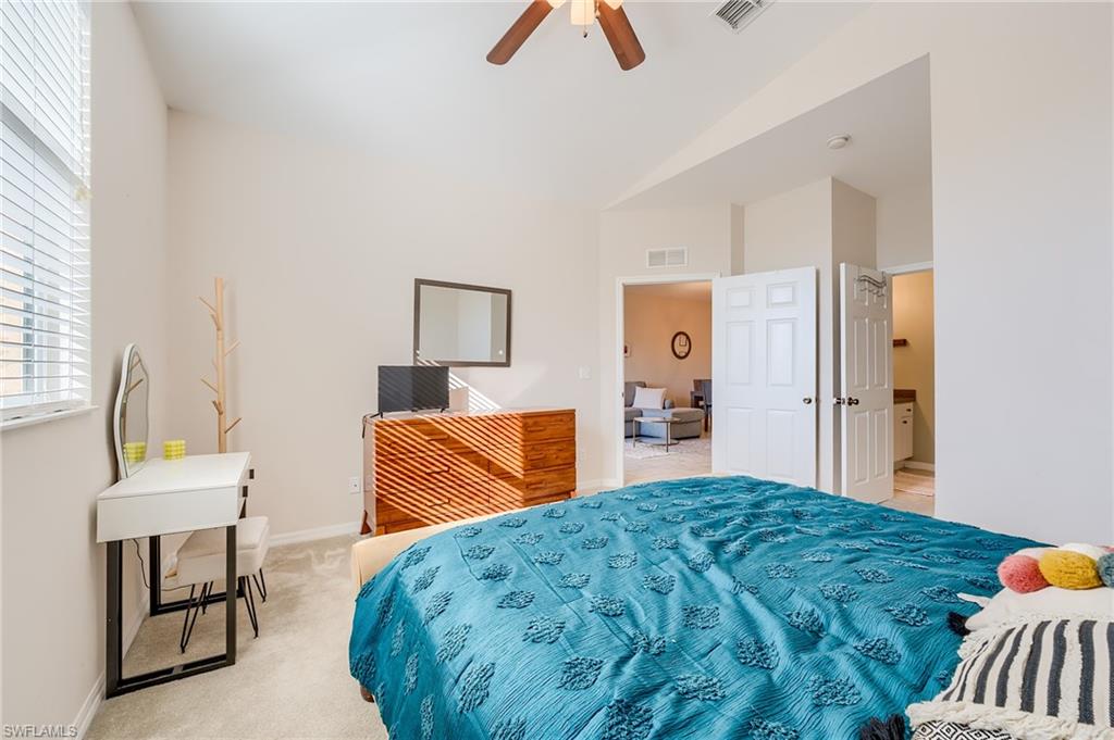 Bedroom featuring ceiling fan, light colored carpet, and vaulted ceiling