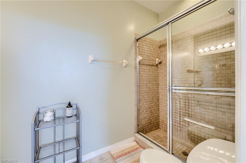 Bathroom with tile patterned floors, toilet, and a shower with shower door