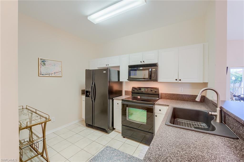 Kitchen featuring light tile patterned flooring, sink, white cabinets, and black appliances
