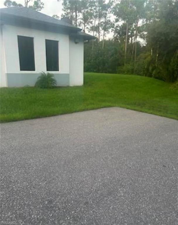 View of side of home featuring a lawn and stucco siding