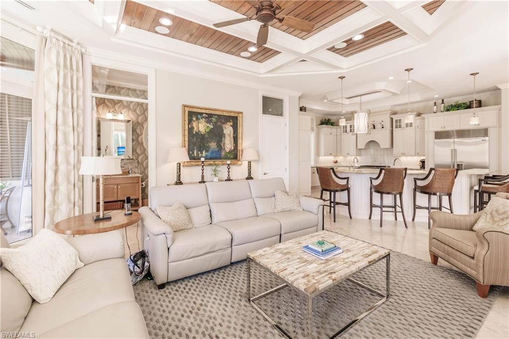 Living room with crown molding, ceiling fan, coffered ceiling, and beamed ceiling