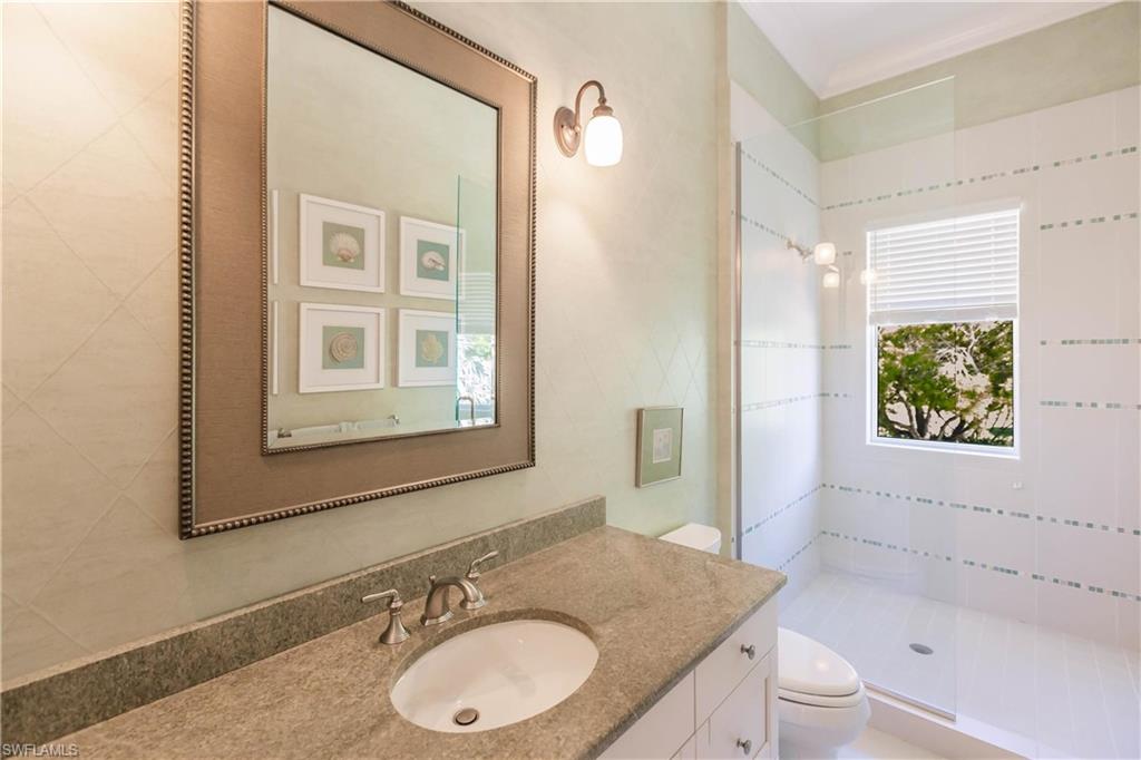 Bathroom with vanity, a tile shower, and toilet