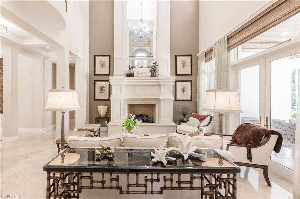 Sitting room featuring french doors, a towering ceiling, a chandelier, and a large fireplace