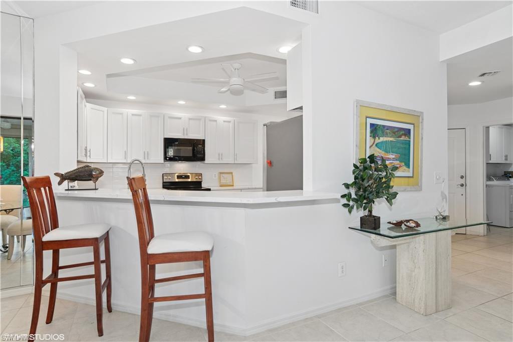 Kitchen with ceiling fan, stainless steel appliances, a peninsula, backsplash, and washer and clothes dryer