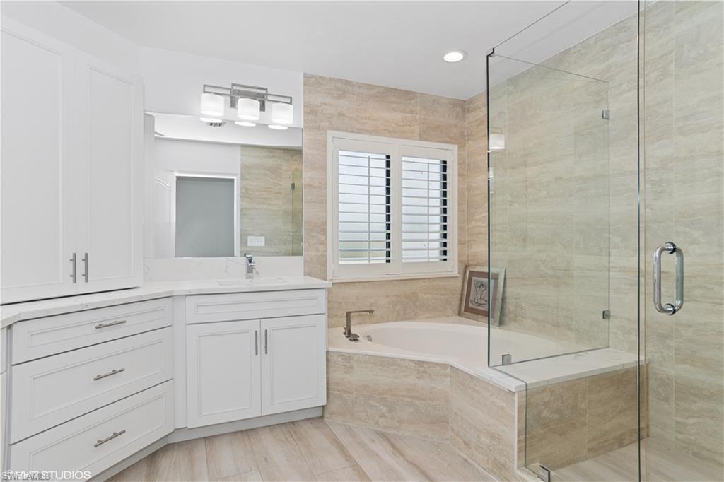 Bathroom featuring a stall shower, a garden tub, and vanity