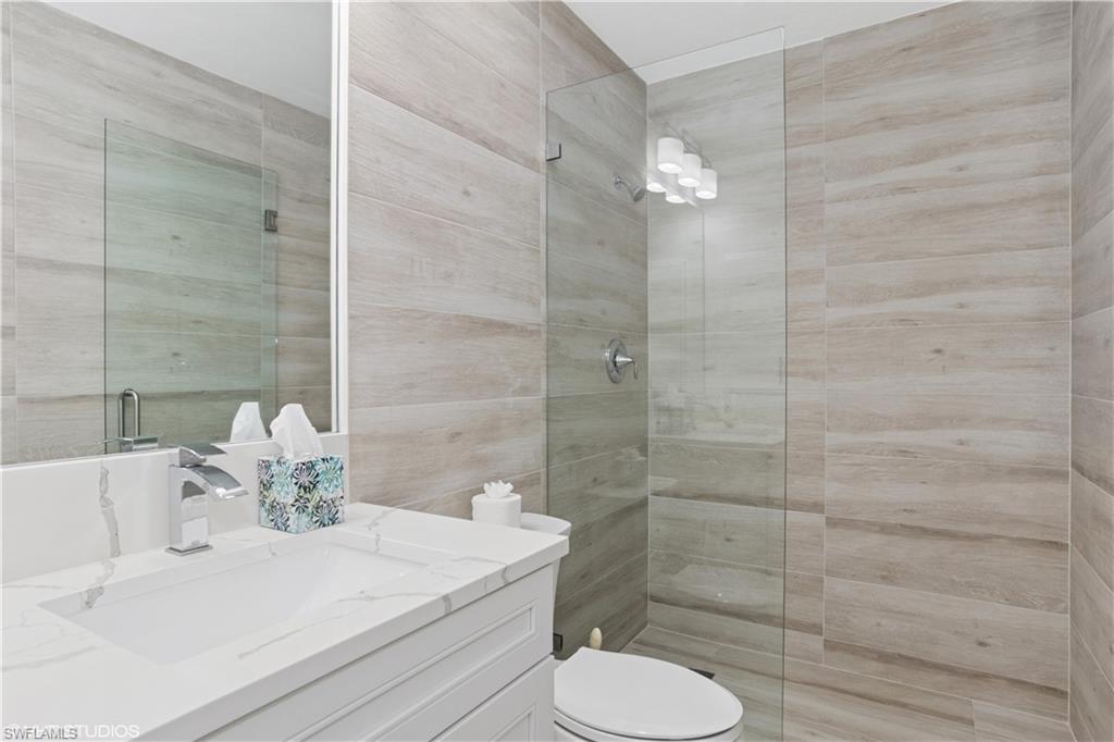 Bathroom with toilet, a tile shower, and vanity