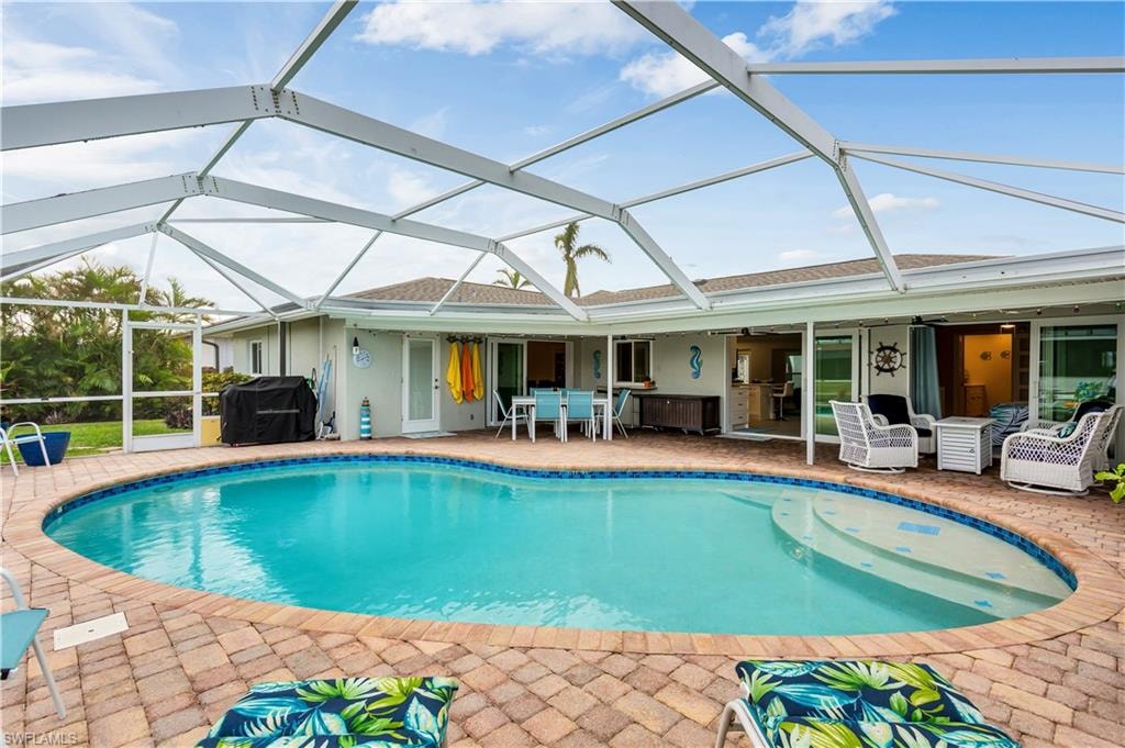 View of pool with ceiling fan, a patio area, a lanai, and grilling area
