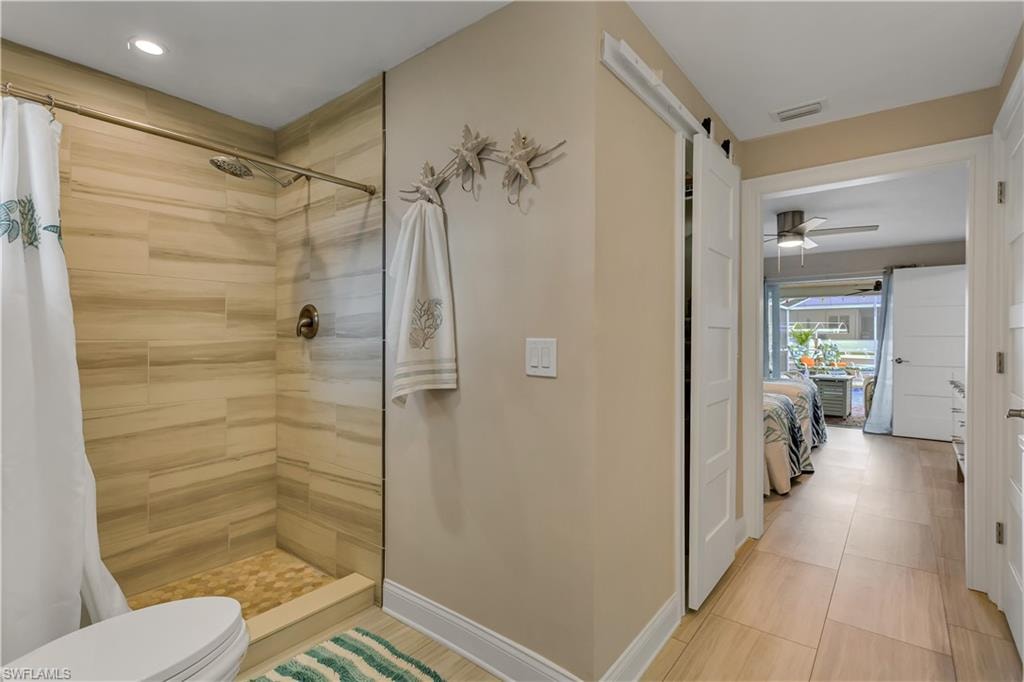 Bathroom featuring ceiling fan, toilet, and walk in shower
