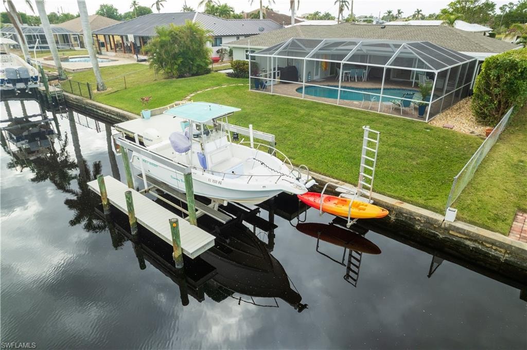 View of dock with a lawn, screened enclosure, and a water view