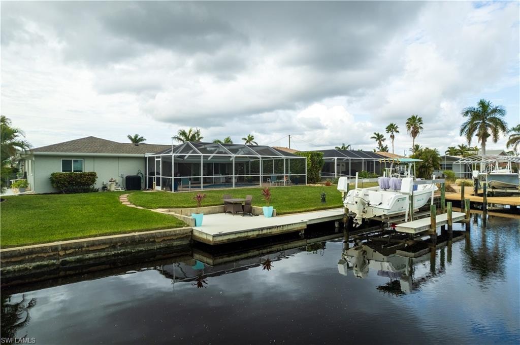 Dock area with a lanai, a water view, and a yard