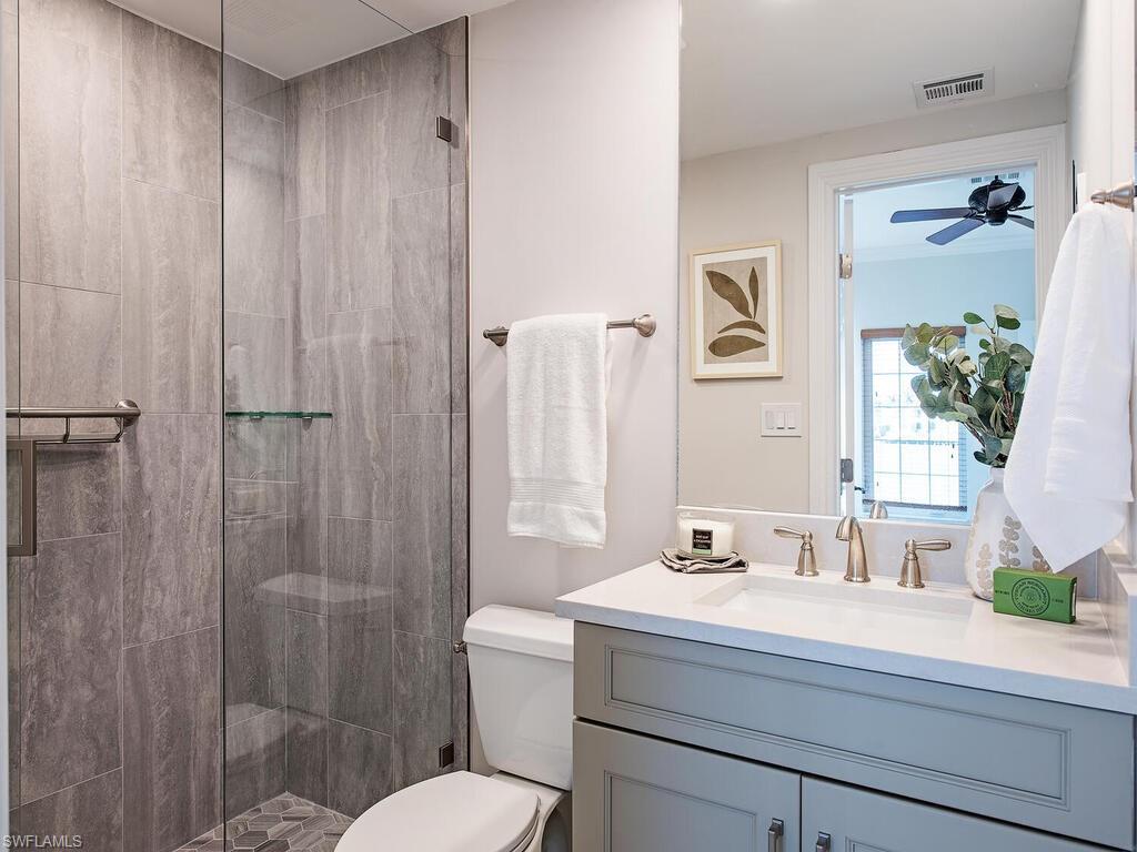 Bathroom with tiled shower, vanity, and toilet