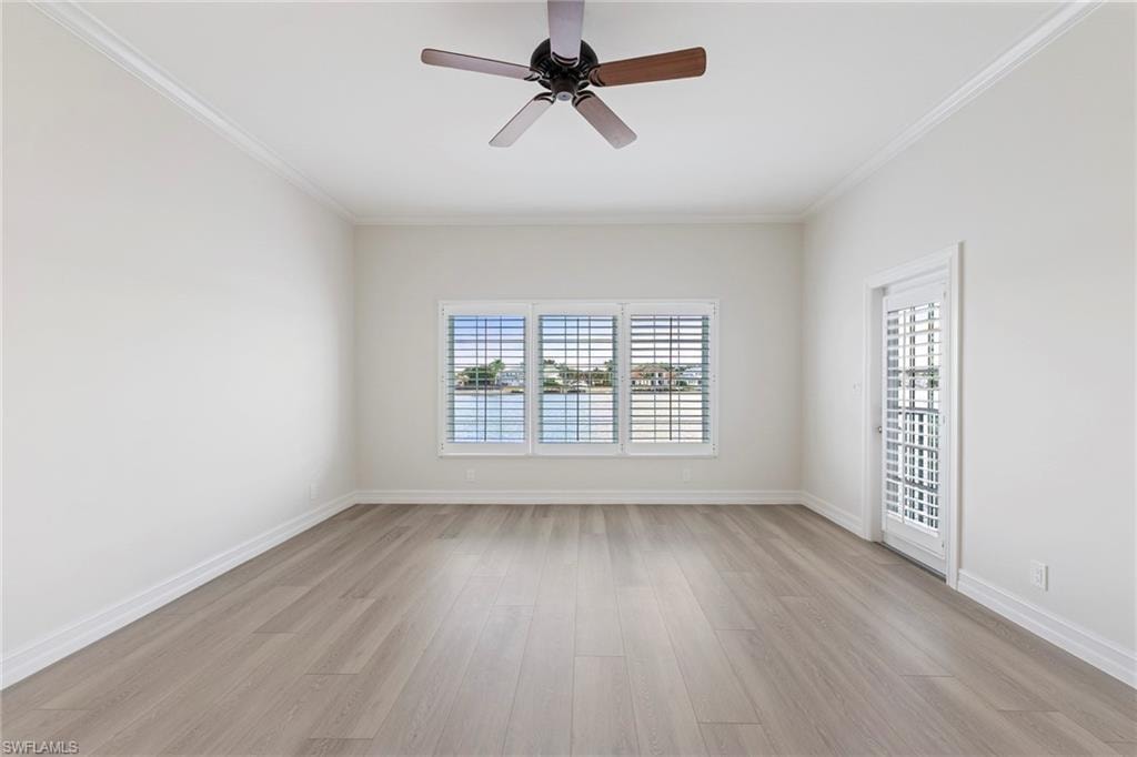 Empty room with ornamental molding, light wood-style flooring, and a ceiling fan