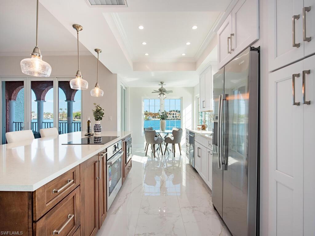 Kitchen with white cabinets, ceiling fan, pendant lighting, a tray ceiling, and appliances with stainless steel finishes