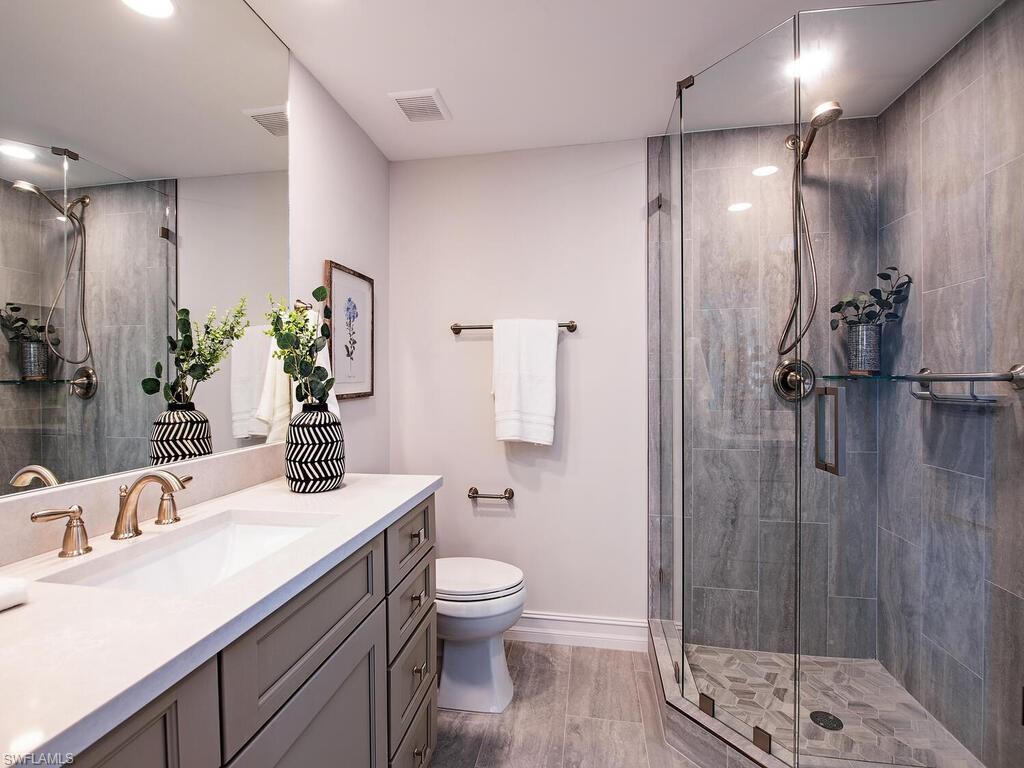 Bathroom with toilet, a shower with door, and vanity