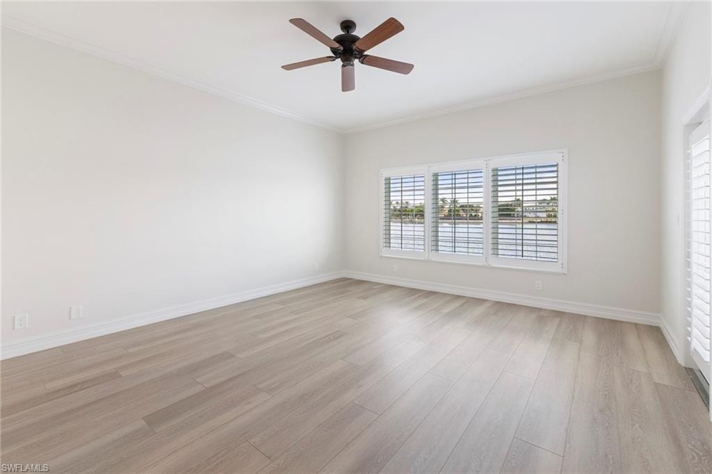 Unfurnished room featuring crown molding, light wood finished floors, and ceiling fan