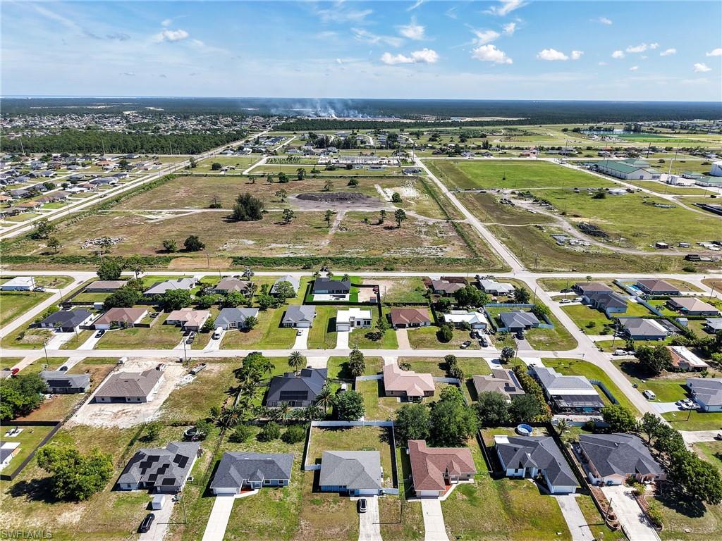 Aerial perspective showcasing a residential neighborhood with a mix of single-story homes and undeveloped land parcels