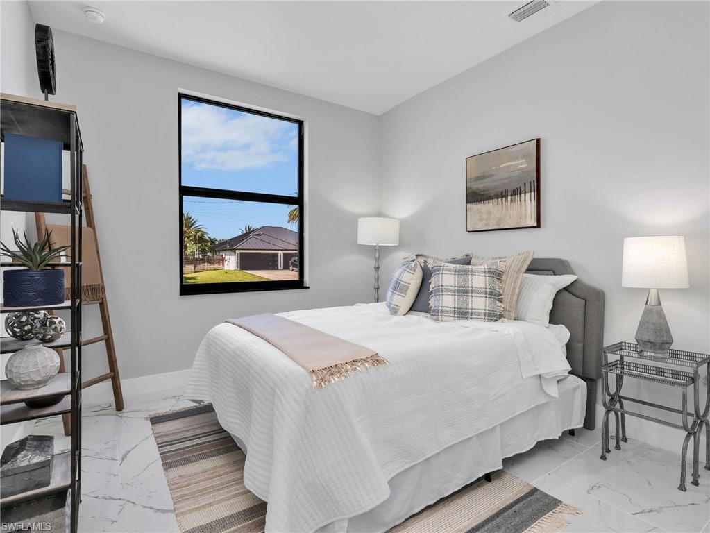 Room featuring large window with black framing, light gray walls, white baseboards, and white marble-look tile flooring