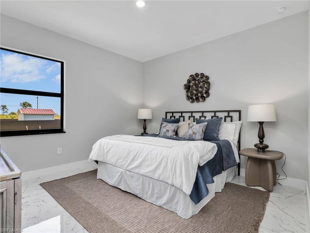 Spacious bedroom featuring light gray walls and large-format white tile flooring