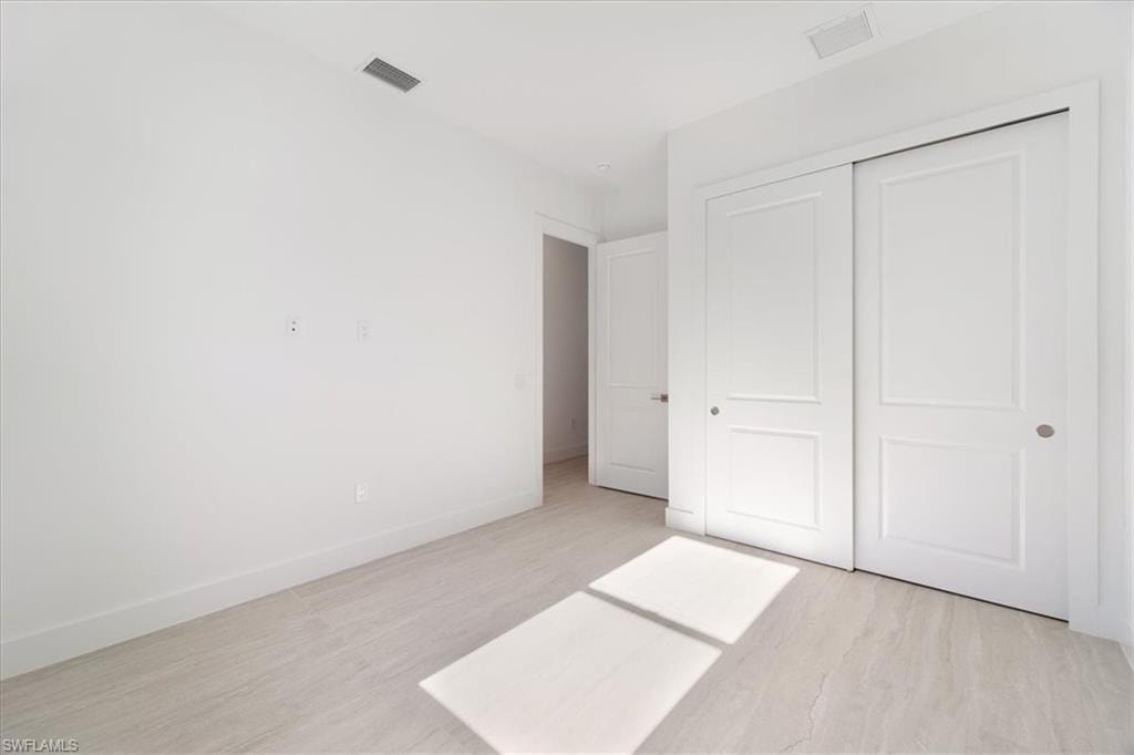 Unfurnished bedroom featuring baseboards, a closet, light wood finished floors, and visible vents