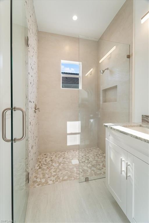 Bathroom featuring vanity, recessed lighting, and a shower stall