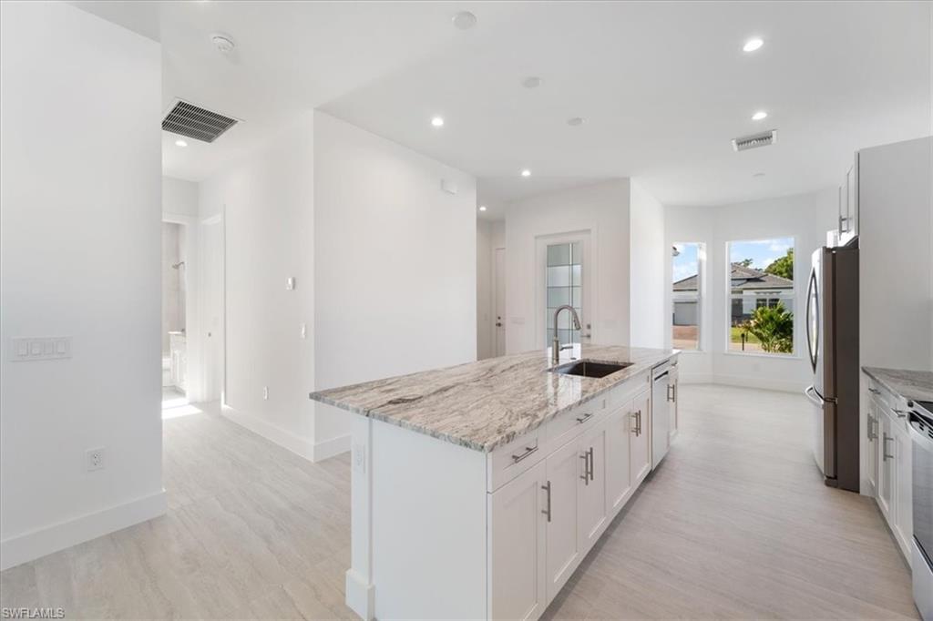 Kitchen with stainless steel appliances, visible vents, a sink, and light wood-type flooring